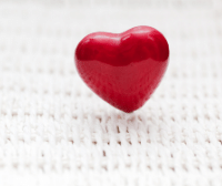 a picture of an inflatable red heart-shaped balloon on a clean white wicker table