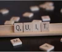 scrabble pieces used to write the word quit